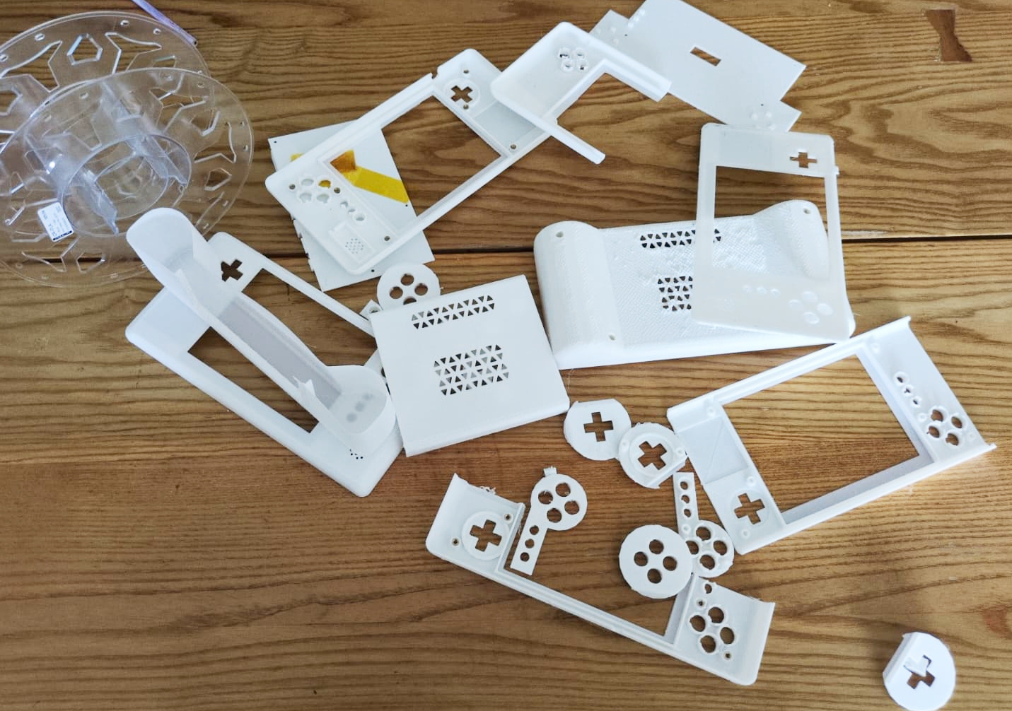 Stack of 3d-printed VapourDeck housings and partial housing components, next to an empty PLA reel